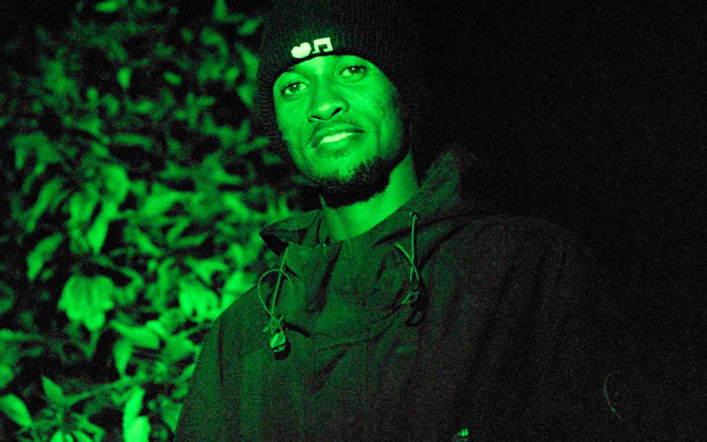 Portrait of a musician lit by green light outdoors