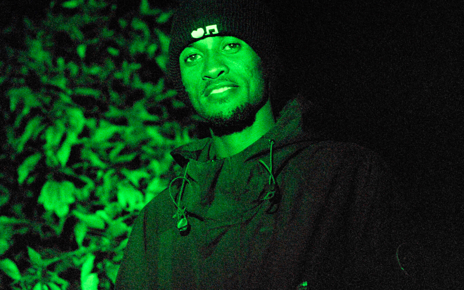 Portrait of a musician lit by green light outdoors
