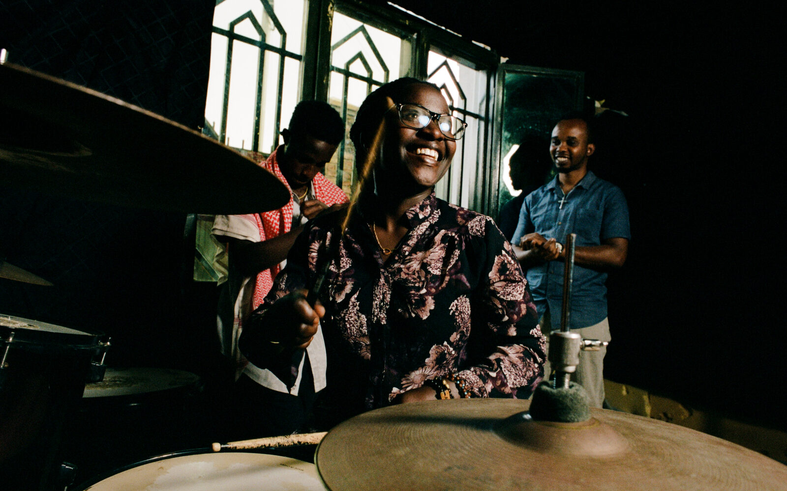 Musicians gathered around drums and instruments indoors