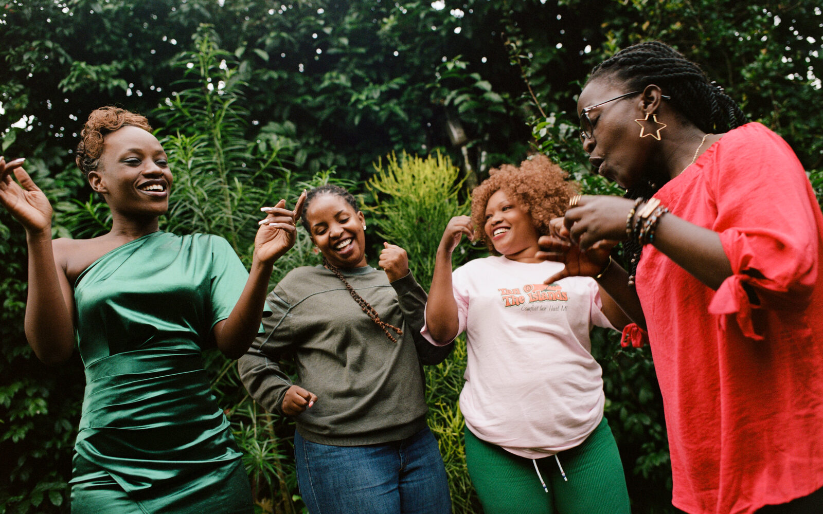 Four people dancing outdoors in a garden